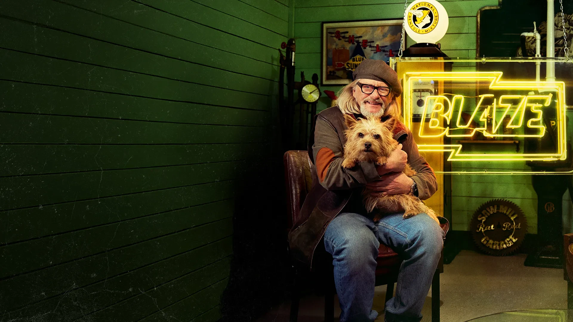 Key art for Junk and Disorderly on Blaze shows host Henry Cole holding a dog, whilst sitting in a shed filled with junk