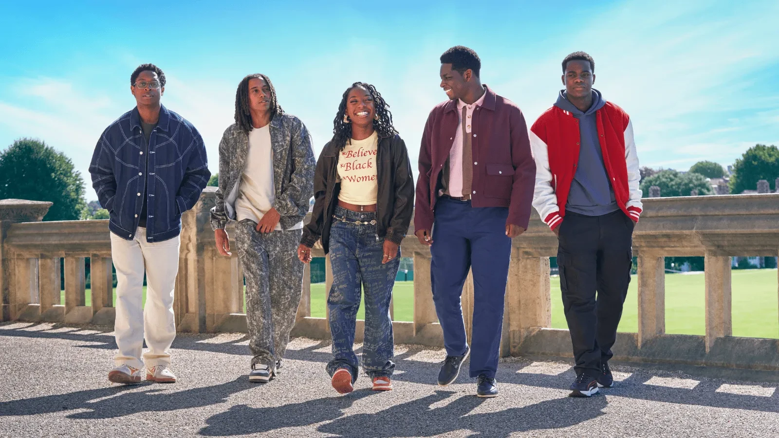 Five young people walking together outdoors on a sunny day, dressed in casual streetwear, with a scenic park landscape in the background