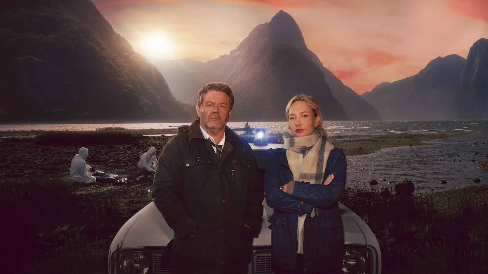 Two people stand in front of a parked car at the edge of a misty lakeside, surrounded by dramatic mountains at sunset. Soft orange and pink light fills the sky, casting long shadows across the water. Behind them, forensic investigators in white suits examine evidence near the shoreline, with a police vehicle’s blue lights glowing faintly in the background. The overall scene blends crime‑scene tension with a cinematic, atmospheric landscape