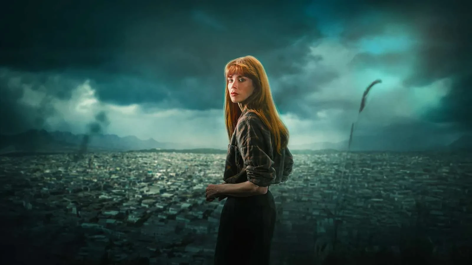 A lone figure with long red hair stands overlooking a vast, densely packed cityscape under a dark, storm‑filled sky. The person is turned slightly to the side, wearing a patterned shirt and holding their hands together, with dramatic lighting casting shadows across the scene. Tall grass in the foreground sways in the wind, and distant mountains fade into the moody horizon