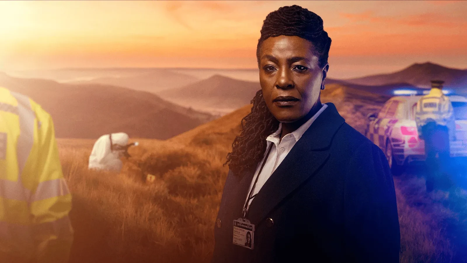 An investigator standing on a windswept hillside at sunset with emergency vehicles, crime‑scene personnel, and rolling mountains in the background.