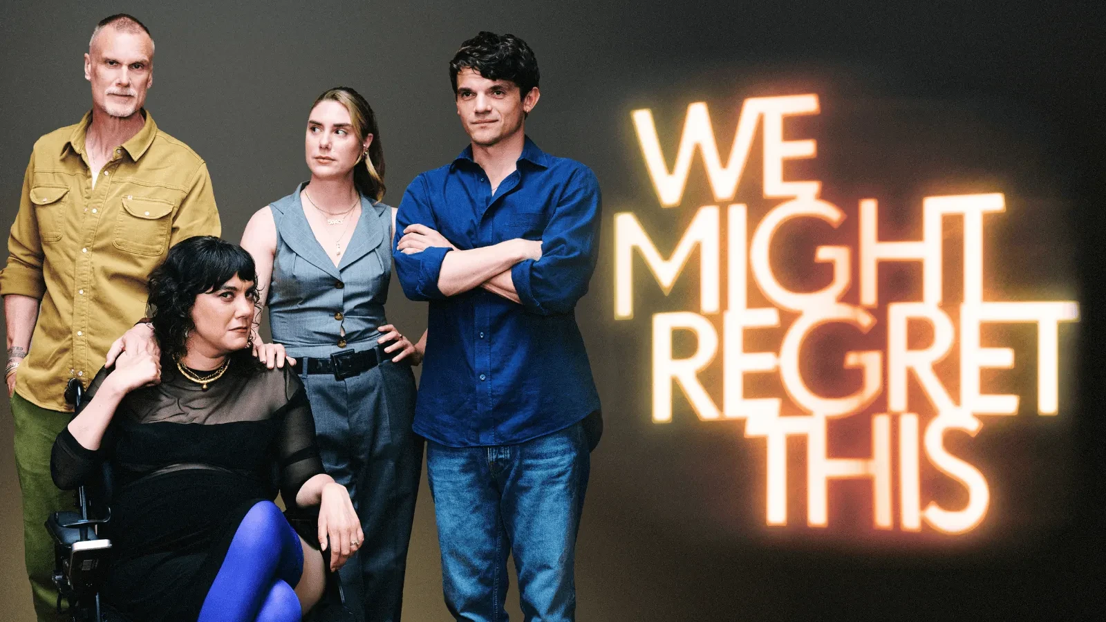 Group of four people posing together in front of a dark backdrop with a bright neon sign reading ‘WE MIGHT REGRET THIS