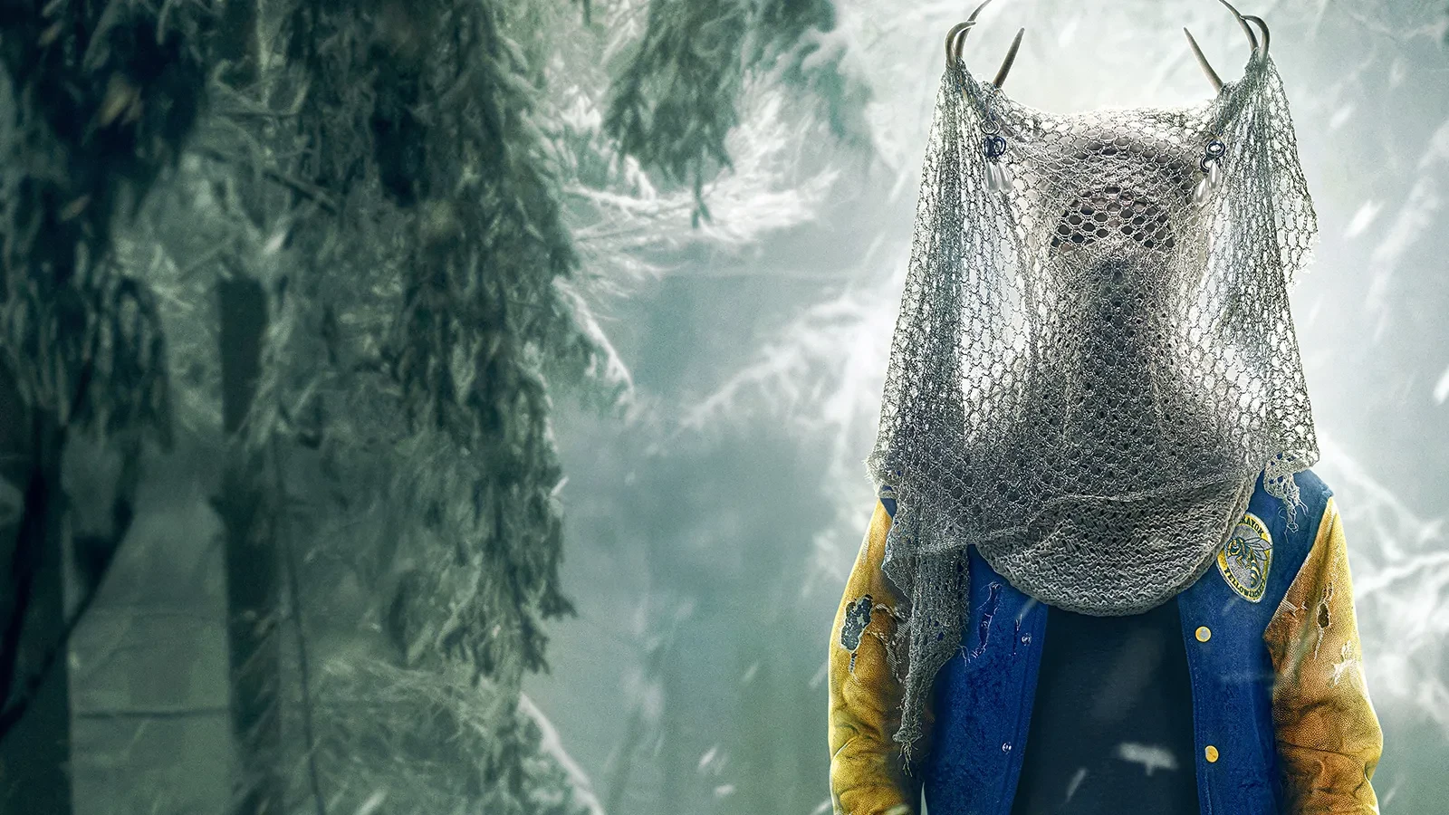 A mysterious figure in a yellow-and-blue varsity jacket standing in a snowy forest, wearing an antler headdress and a mesh veil that obscures the head.