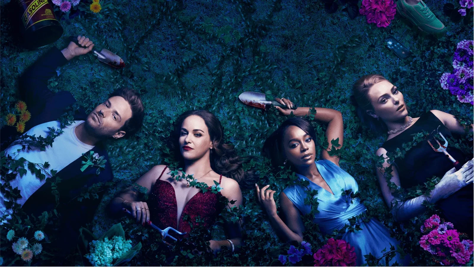 Four people lie on a grass-covered ground surrounded by flowers and gardening tools, each holding an object such as a wine bottle or small gardening fork. 