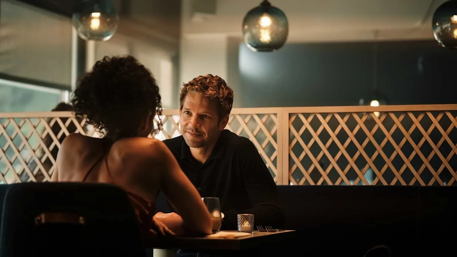 Jim Bergerac talks quietly with a woman in a softly lit restaurant, a tense and intimate moment from the TV crime drama Bergerac.