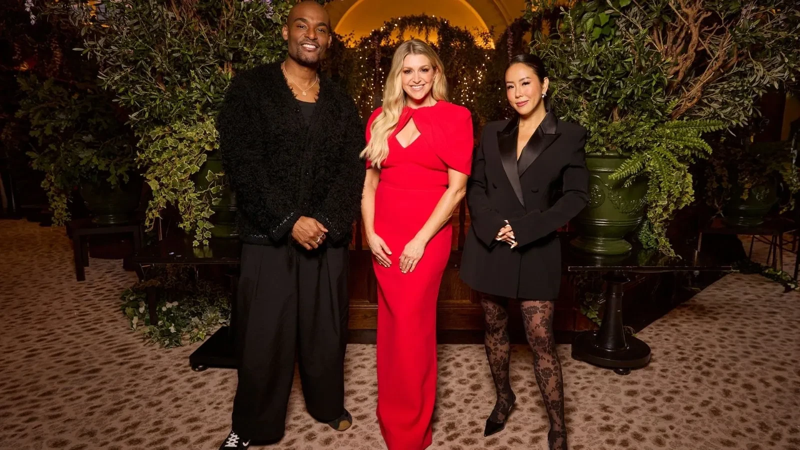 One male and two female celebrities stood in front of greenery in a resteraunt