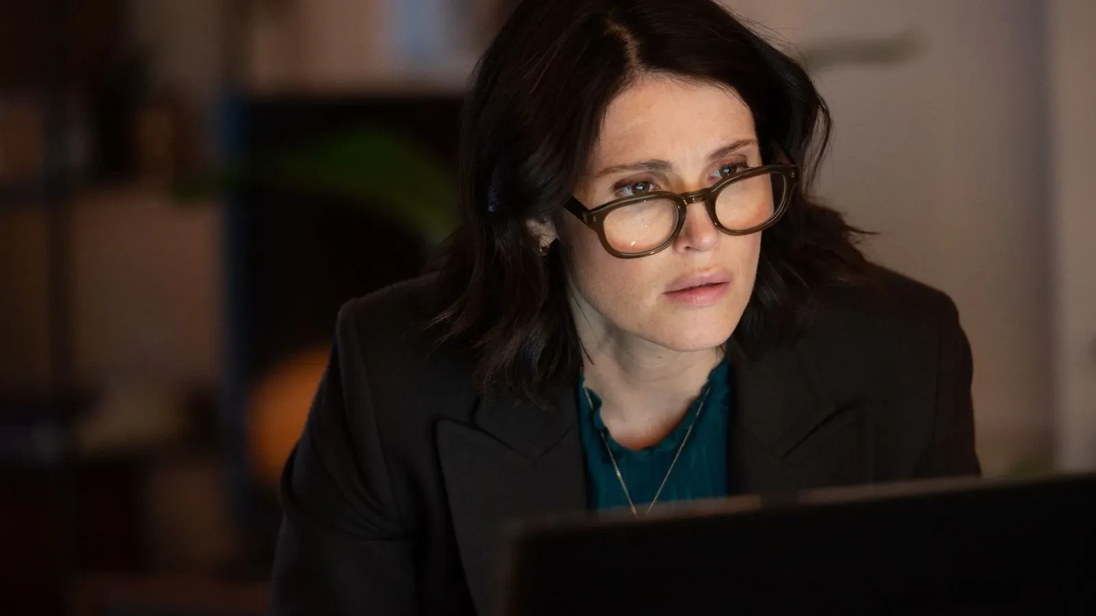 Close-up of an intelligence officer wearing glasses and working on a laptop in a dimly lit interior, from the TV drama Secret Service
