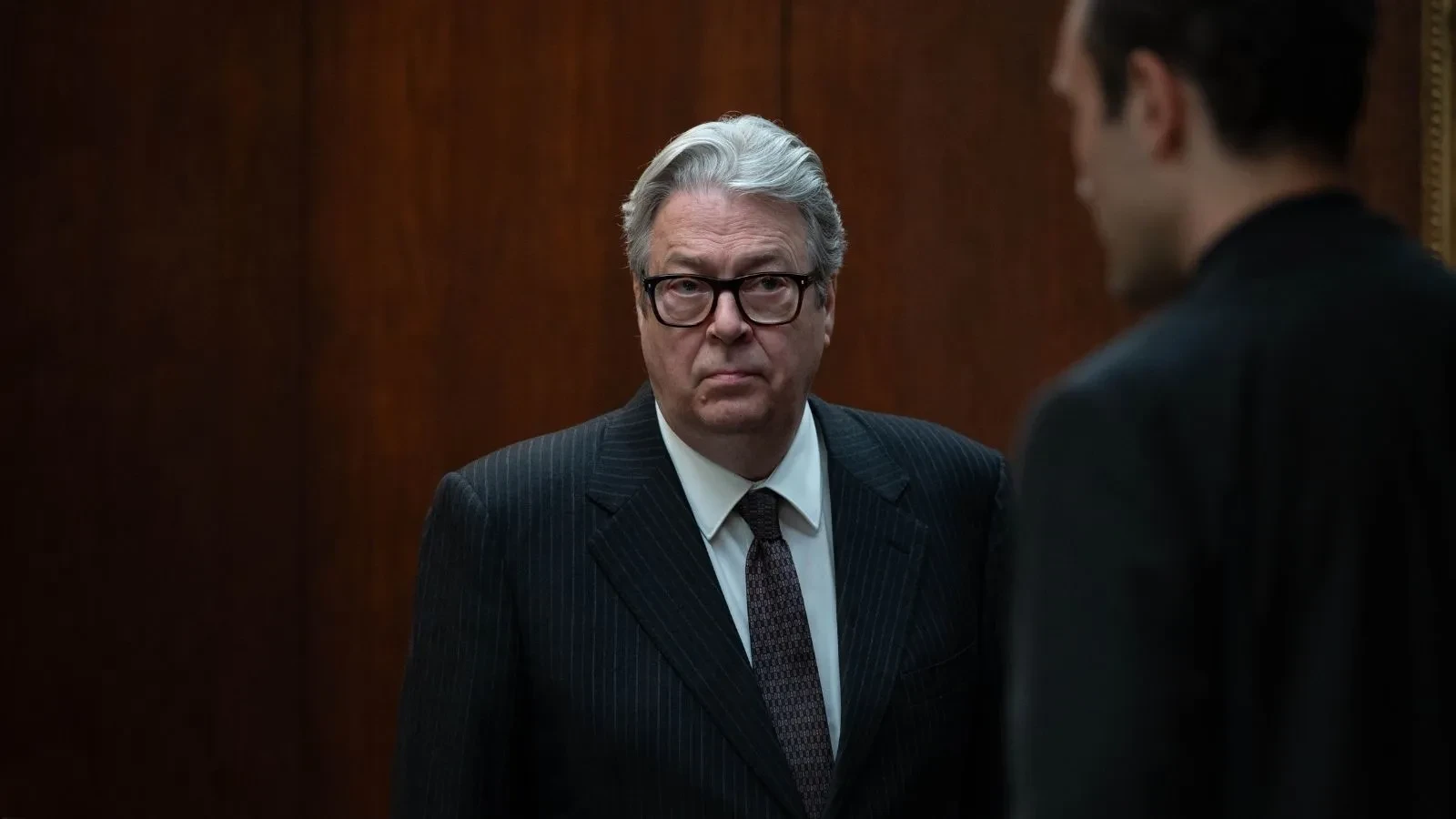 Senior adviser in a wood‑panelled office speaking with another official, from the political drama series Secret Service