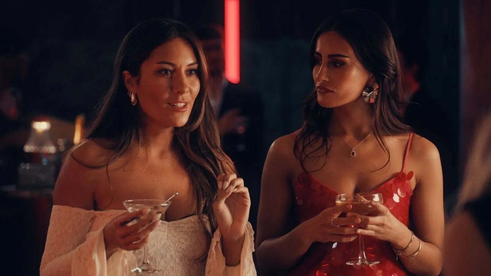 Two woman dressed for a night out holding cocktails in a bar