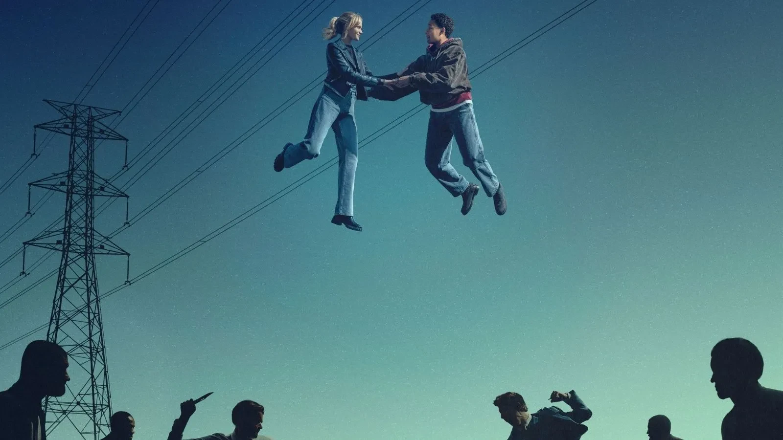 Two people suspended mid‑air while holding hands above a group of silhouetted figures, set against a clear sky with electricity pylons and overhead power lines in the background.