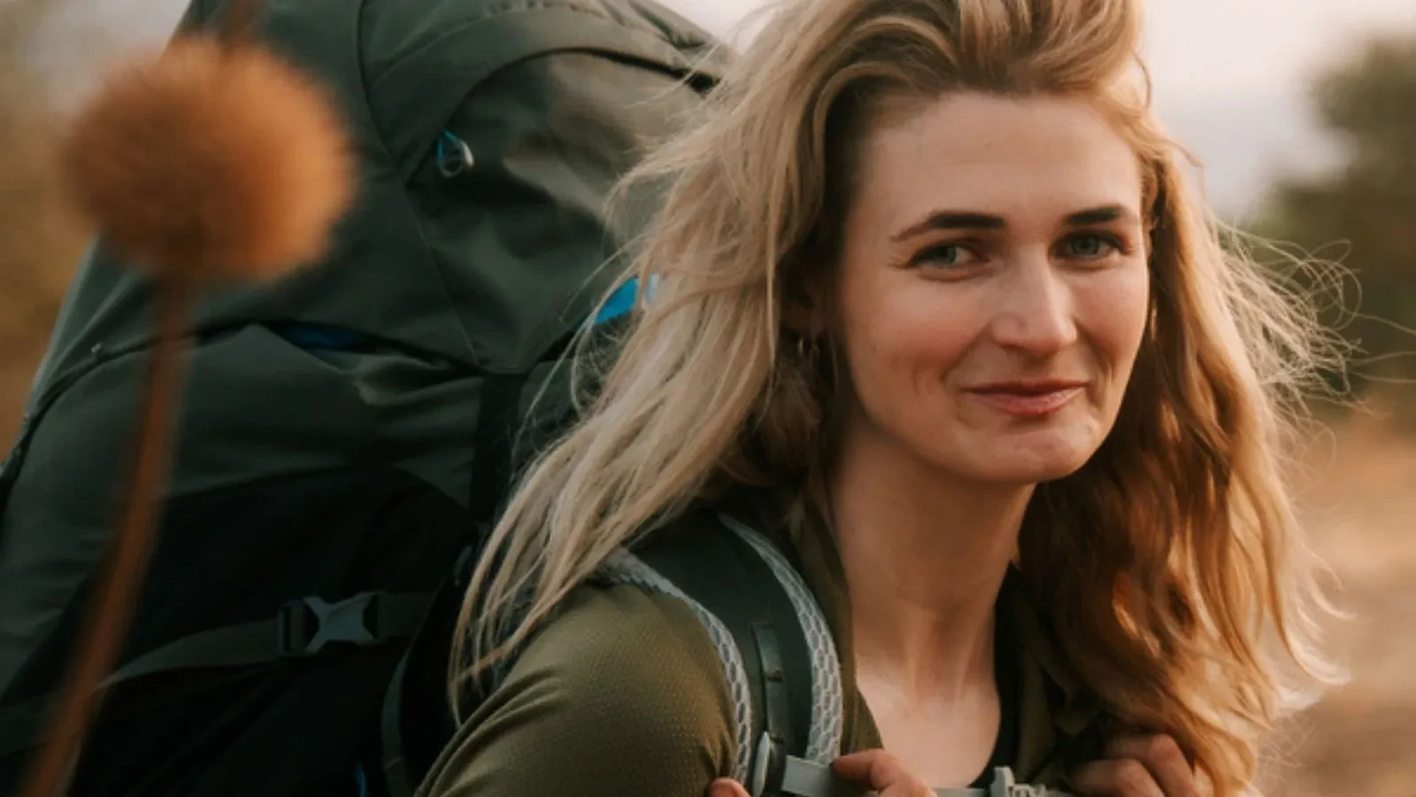 Close-up of a traveller carrying a large backpack on an African wilderness trek, surrounded by natural landscape and warm light.