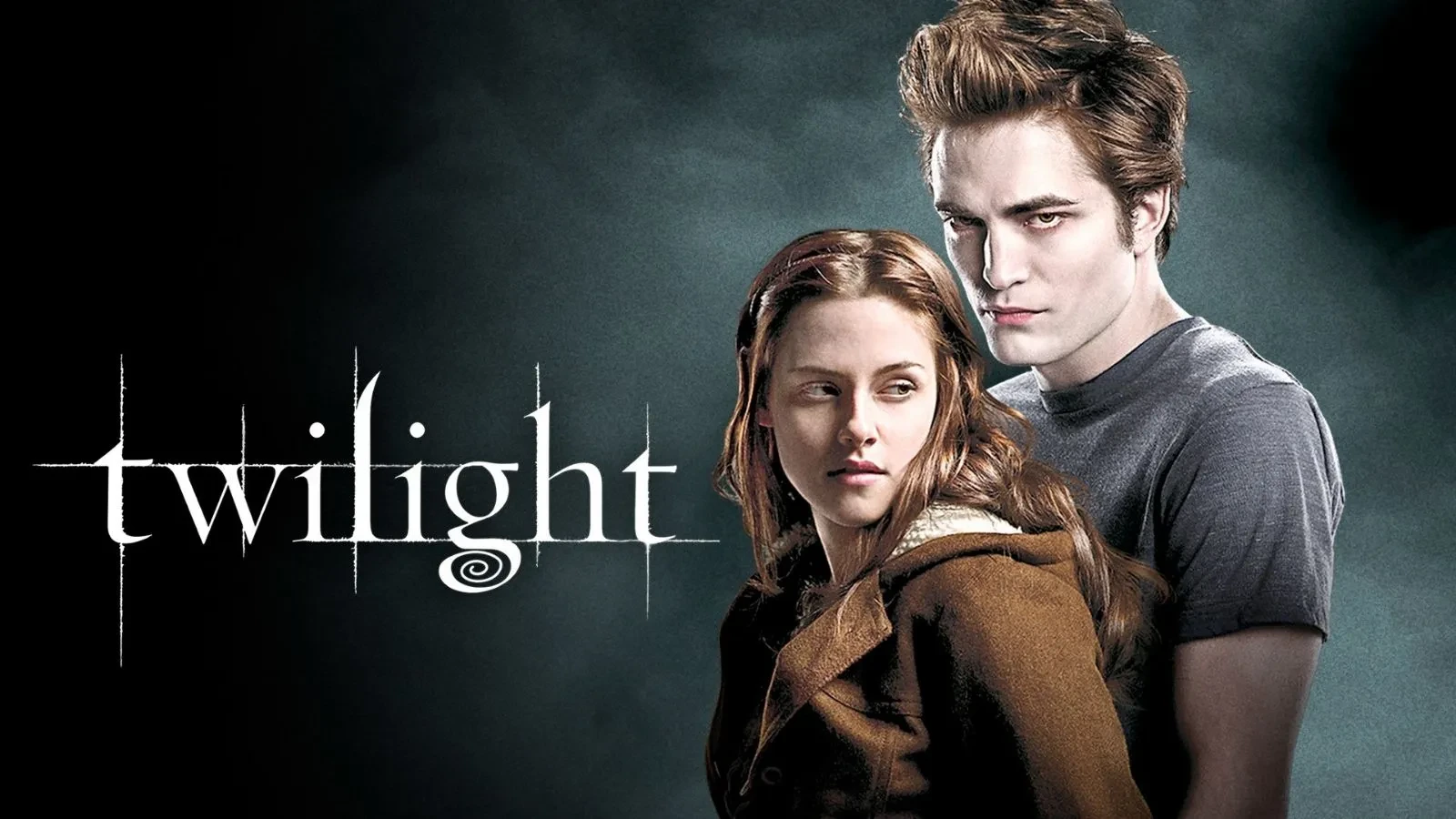A young brunette woman wearing a brown coat stood in front of a pale man wearing a grey t shirt with writing that reads "twilight"