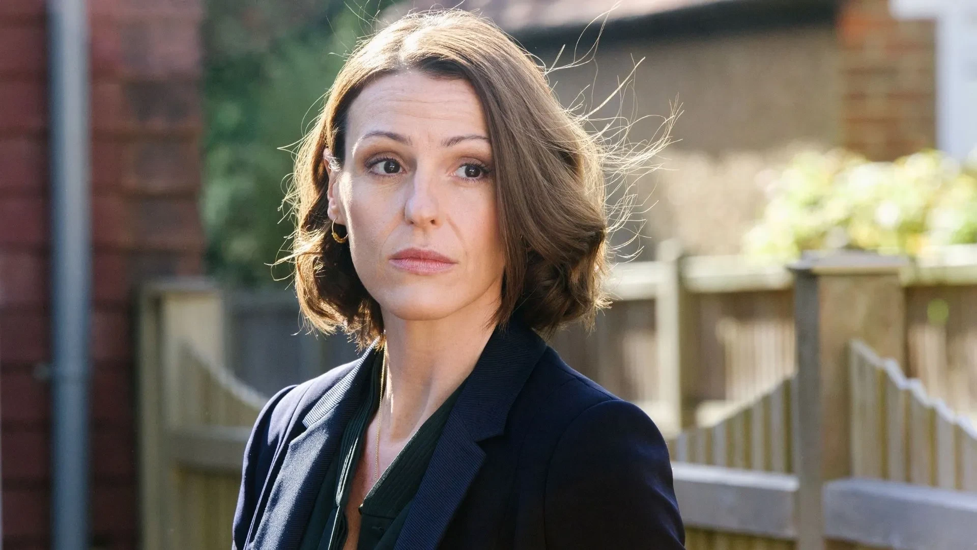 Promotional image from Doctor Foster showing a character standing outdoors in a residential street setting.