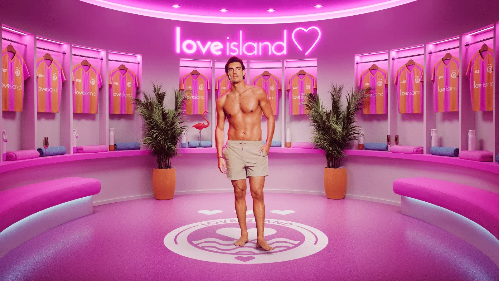 Lorenzo from season 13 of Love Island stood in the pink Love Island locker rooms with Love island Football shirts behind him