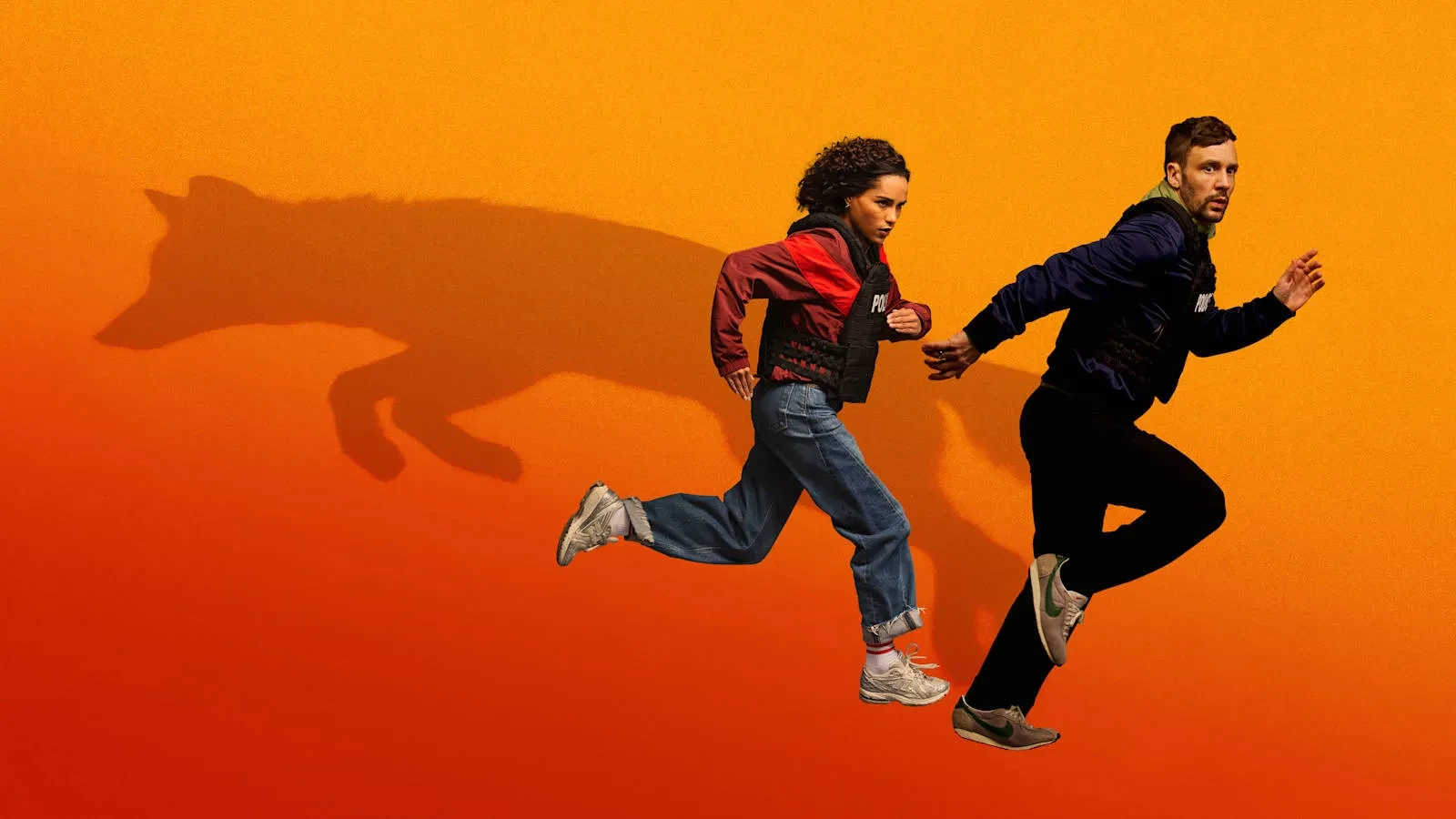 Nick Blood and Saffron Hocking as Leo and Bell in UKTVs new drama Hit Point. A man and woman in casual clothing running against an orange background with the shadow of a dog coming off them.